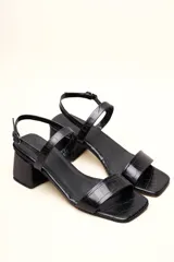 Sandalia de cuero vacuno color negro con textura de cocodrilo, taco cuadrado de 4 cm, punta cuadrada y dos tiras finas, una en el empeine y otra con hebilla en el tobillo.