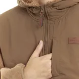 Campera marrón con capucha forrada en sherpa, cierre frontal con cremallera, bolsillos laterales y parche con logo de la marca en el pecho.