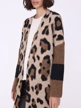 Spolverino largo con estampado animal print en tonos beige, marrón y negro. Tiene mangas largas con detalle de rayas horizontales en marrón y negro, y flecos en el ruedo.