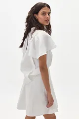 Minifalda blanca de lino con silueta evasé, tiro alto y cierre trasero oculto.