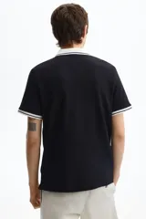 Polo de manga corta confeccionado en piqué de algodón, con cuello y bordes de mangas en color blanco con detalles de líneas negras. Presenta cierre frontal con botones y un corte ajustado.