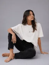 Remera de corte oversize, color crudo, con cuello redondo y mangas cortas. Presenta un estampado minimalista en el pecho con la frase 'THE NEW COOL' y la palabra 'CRUDA' debajo.