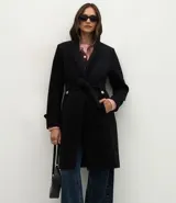 Saco femenino de corte midi confeccionado en polyvelour, con diseño cruzado, cuello tipo blazer, mangas largas con detalles en puños, cierre frontal con lazo ajustable en la cintura y botones metalizados decorativos.