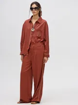 Camisa azul de corte holgado, con cuello camisero, mangas largas con detalles en los puños, bolsillo frontal con bordado y cierre delantero con botones.