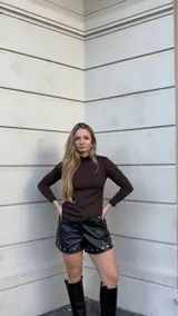 Polera de manga larga en color chocolate, confeccionada en tejido jersey térmico. Presenta un diseño ajustado al cuerpo con cuello alto y corte asimétrico en el ruedo.