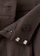 Pantalón balloon de tiro medio color marrón oscuro, con diseño de pinzas, trabillas y bolsillos laterales. Cuenta con cierre de gancho y cremallera.
