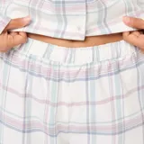 Conjunto de pijama de dos piezas, compuesto por una camisa de manga larga con cuello y botones, y un pantalón largo con cintura elástica. Diseño a cuadros en tonos pastel.