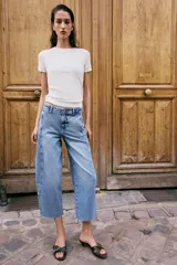 Jeans de tiro alto con corte barrel, pernera holgada que se estrecha hacia el tobillo y bajo deshilachado. Presenta costuras verticales decorativas en el frente y cierre frontal con cremallera y botón.