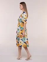 Vestido midi de calce holgado y caída fluida con escote en V cruzado, cintura elastizada fruncida y mangas cortas con volados superpuestos. Cuenta con un diseño estampado de flores grandes en tonos amarillo, blanco, azul marino y verde.