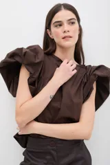 Blusa color marrón chocolate con mangas abullonadas de gran volumen y diseño estructurado.