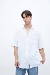 Camisa de manga corta color celeste claro, con cuello solapa clásico y bolsillo en el pecho. Presenta una textura ligera y un calce regular.