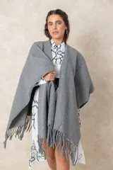Ruana abierta de color beige, confeccionada en tejido de punto con terminación de flecos en el ruedo.