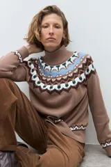 Polera de tejido de punto en color tostado, con diseño de estampado geométrico tipo nórdico en la zona del cuello, hombros y puños. Presenta cuello alto acanalado y mangas largas.