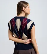 Chaleco de punto de cuello en V sin mangas, con estampado de rombos argyle en tonos azul marino, bordó y beige. Presenta bordes acanalados en el cuello y sisas.