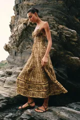 Vestido midi de broderie en tonos mostaza y marrón, con escote en V, tirantes finos ajustables, abertura cut-out en la cintura y espalda con nido de abeja elástico.