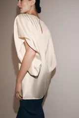 Top fluido de manga corta de Zara Woman Collection, confeccionado en hilatura de viscosa de color crudo. Cuenta con cuello barco, bajo recto y cierre en la espalda con pequeña abertura y botón.