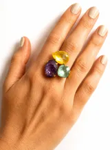 Anillo artesanal hecho en Grecia con bronce enchapado en oro y cristales Swarovski en tonos violeta, amarillo y aqua. Cuenta con un diseño ajustable de múltiples piedras facetadas.
