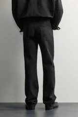 Jeans slim straight fit para hombre, confeccionados en denim de algodón negro sin lavados. Presentan diseño de tiro bajo, pierna recta y cinco bolsillos, con cierre frontal de botonadura.