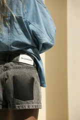 Short de jean gris oscuro con efecto degradé simulando los bolsillos y parche negro con logo bordado en el bolsillo trasero.