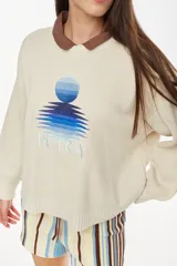 Sweater de punto color amarillo con diseño relajado y escote redondo, confeccionado en mezcla de algodón y acrílico. Presenta un bordado frontal con motivo de sol y reflejos acompañado de la inscripción "Petra".