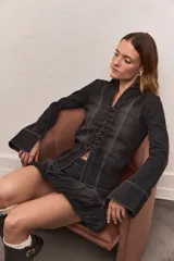 Camisa de jean negro con diseño trenzado, cuello clásico, cierre frontal con cordones y mangas largas con puños anchos.