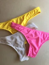 Pack de tres bombachas de bikini tipo colaless, una amarilla, una blanca y una rosa.