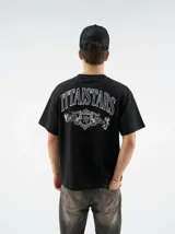 Remera negra de manga corta y corte oversize, con estampa gráfica en blanco en el frente y en la espalda con diseño de tipografía y escudo heráldico.