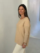 Sweater de punto color beige con diseño de trenzas horizontales, cuello redondo y mangas largas con puños ajustados.