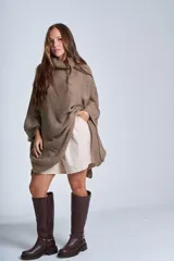 Poncho tejido color beige, con cuello alto y corte asimétrico.