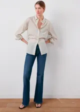Jeans de denim azul oscuro con diseño flare, tiro alto, trabillas y cinco bolsillos.