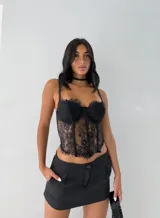 Corset de encaje negro con estructura de varillas, copas preformadas y bordes con terminación desflecada. Cuenta con breteles finos ajustables.