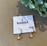 Aros de argolla dorada con dije redondo de fimo color naranja con estampado floral y bolita dorada.