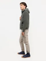 Chaqueta híbrida para hombre con frente acolchado de nylon y mangas de tejido de punto. Cuenta con cierre frontal, capucha y puños acanalados.