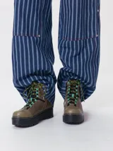 Botas de cuero estilo trekking, en combinación de colores verde, marrón y gris, con plataforma de goma negra, cordones bicolor inspirados en cuerdas de escalada y pasadores en tono rojizo.