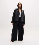 Campera estilo biker confeccionada en poliuretano con base de viscosa, forrada en poliéster. Presenta cuello con solapas, cierre frontal con cremallera metálica, bolsillos laterales con cierre y detalles de botones a presión.