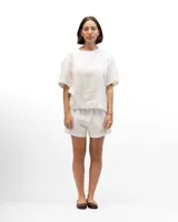 Remera de lino con corte holgado, cuello redondo y mangas cortas. Presenta un diseño minimalista con detalle de botones en la espalda.