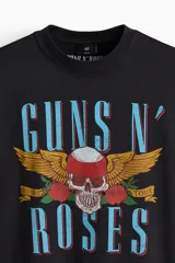 Remera oversized de algodón pesado color negro, con cuello redondo acanalado, hombros caídos y estampa frontal de Guns N' Roses con diseño de calavera y rosas.