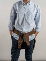 Camisa de corte regular confeccionada en tejido Oxford de algodón, con diseño de rayas verticales finas. Presenta cuello abotonado, cierre frontal con botones y un bolsillo en el pecho.