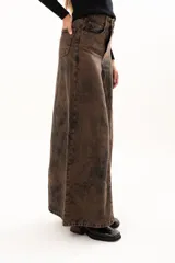 Pantalón de jean de tiro alto con corte wide leg y diseño de paneles verticales. Presenta un acabado lavado con efecto desgastado en tono chocolate, bolsillos funcionales y cierre frontal con botón metálico.