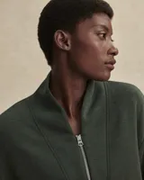 Buzo de tejido ligero DoubleSoft®, color verde oliva, con cuello alto y cierre frontal parcial. Presenta un corte ligeramente recortado, hombros caídos y puños pronunciados.