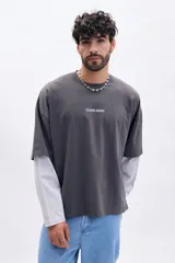 Remera de manga corta gris oscuro con cuello redondo y estampado frontal "EXCLUSIVE ARCHIVE" en blanco. Presenta un efecto de doble manga con una capa inferior de manga larga en color gris claro.