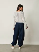Pantalón slouchy de denim azul oscuro con pinzas en la cintura, bolsillos laterales y puños fruncidos con elástico en los tobillos.