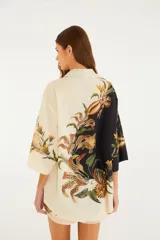 Camisa holgada de algodón con diseño bicolor (mitad negra y mitad cruda) y estampado surrealista de conchas marinas, estrellas de mar y elementos botánicos. Cuenta con cuello camisero, cierre frontal de botones y mangas anchas.