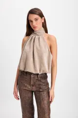 Blusa sin mangas con cuello halter alto y diseño fluido con pliegues frontales. Confeccionada en tela con textura sutil.
