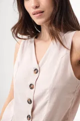 Chaleco color beige de lino con corte sastrero y cierre frontal con botones marrones.