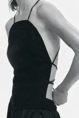 Vestido largo color negro con cuerpo de crochet en la parte superior, escote halter con tirantes finos y falda fluida con leve vuelo confeccionada en mezcla de lyocell. Presenta diseño de espalda descubierta.