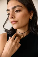 Collar con dije de acero quirúrgico en forma de flor de lirio, montado sobre un tiento de cuero encerado largo.