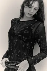 Camisa de mesh transparente con mangas largas y cuello redondo, decorada con bordados de cuentas y lentejuelas en diseño floral.
