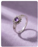 Anillo de plata 925 con piedra amatista central en corte cabujón, rodeada por un detalle de filigrana y diseño calado en los laterales del cuerpo.