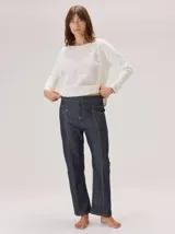 Jean de corte recto confeccionado en denim azul oscuro, con costuras a la vista en color rojo contrastante. Presenta un diseño de tiro alto con bolsillos frontales y cierre de botón.